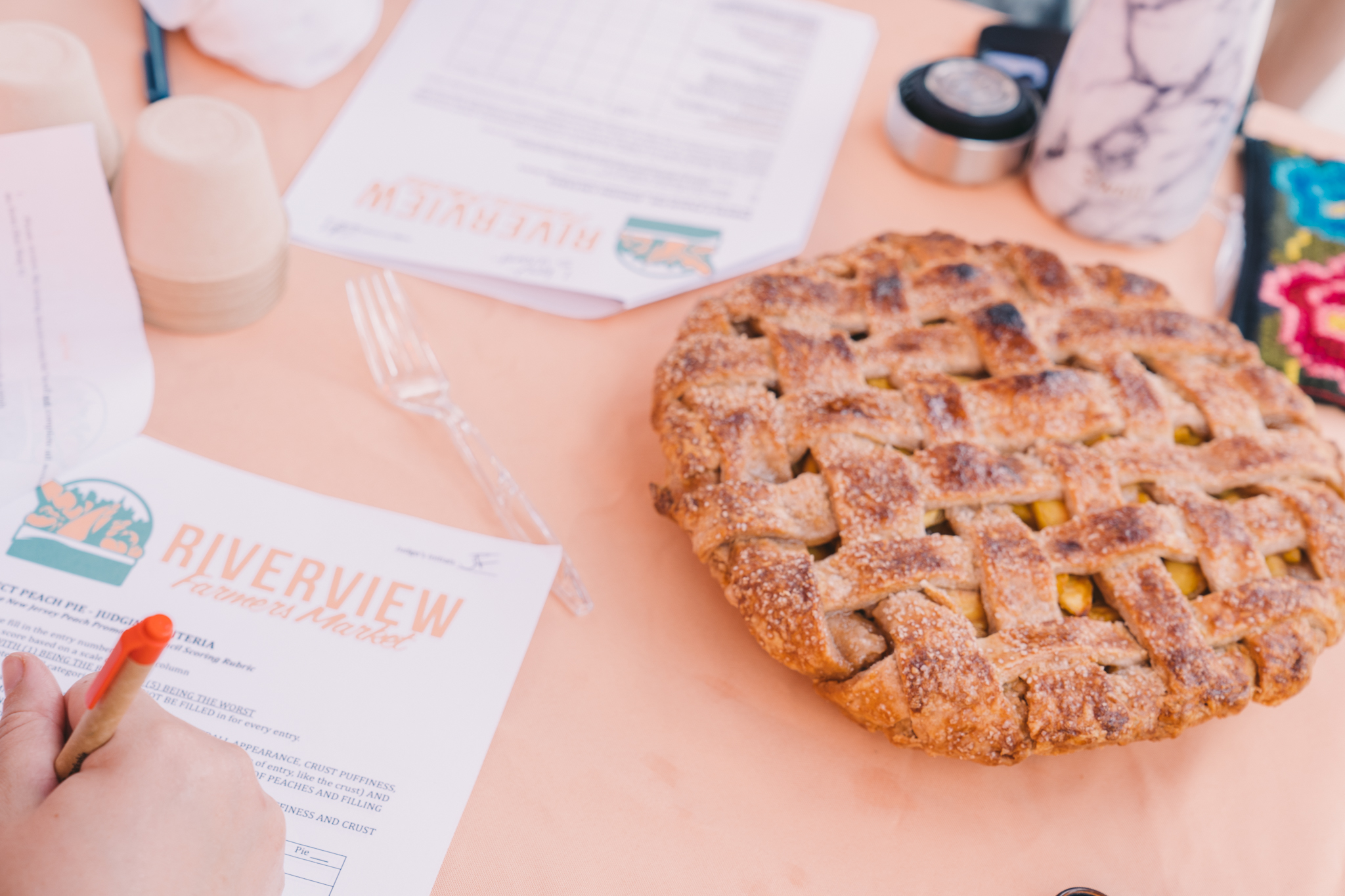 A peach pie with a golden lattice crust sits on a table next to a judge's assessment paper.