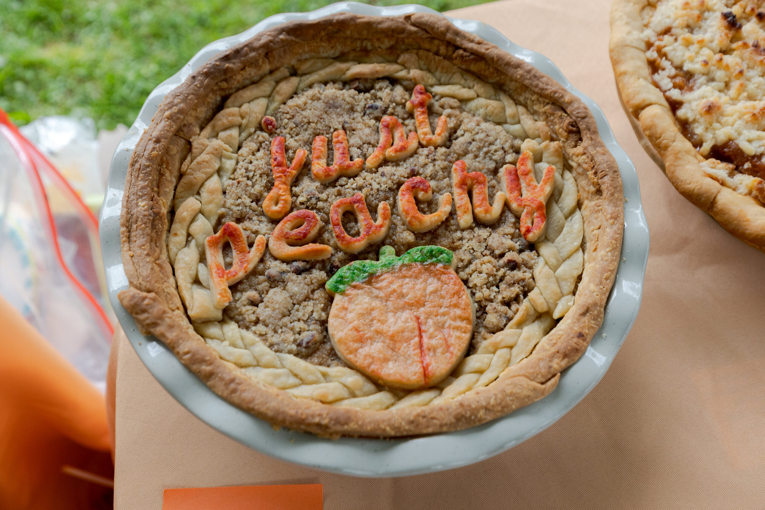 A peach pie that has "Just Peachy" spelled out with crust on the top.